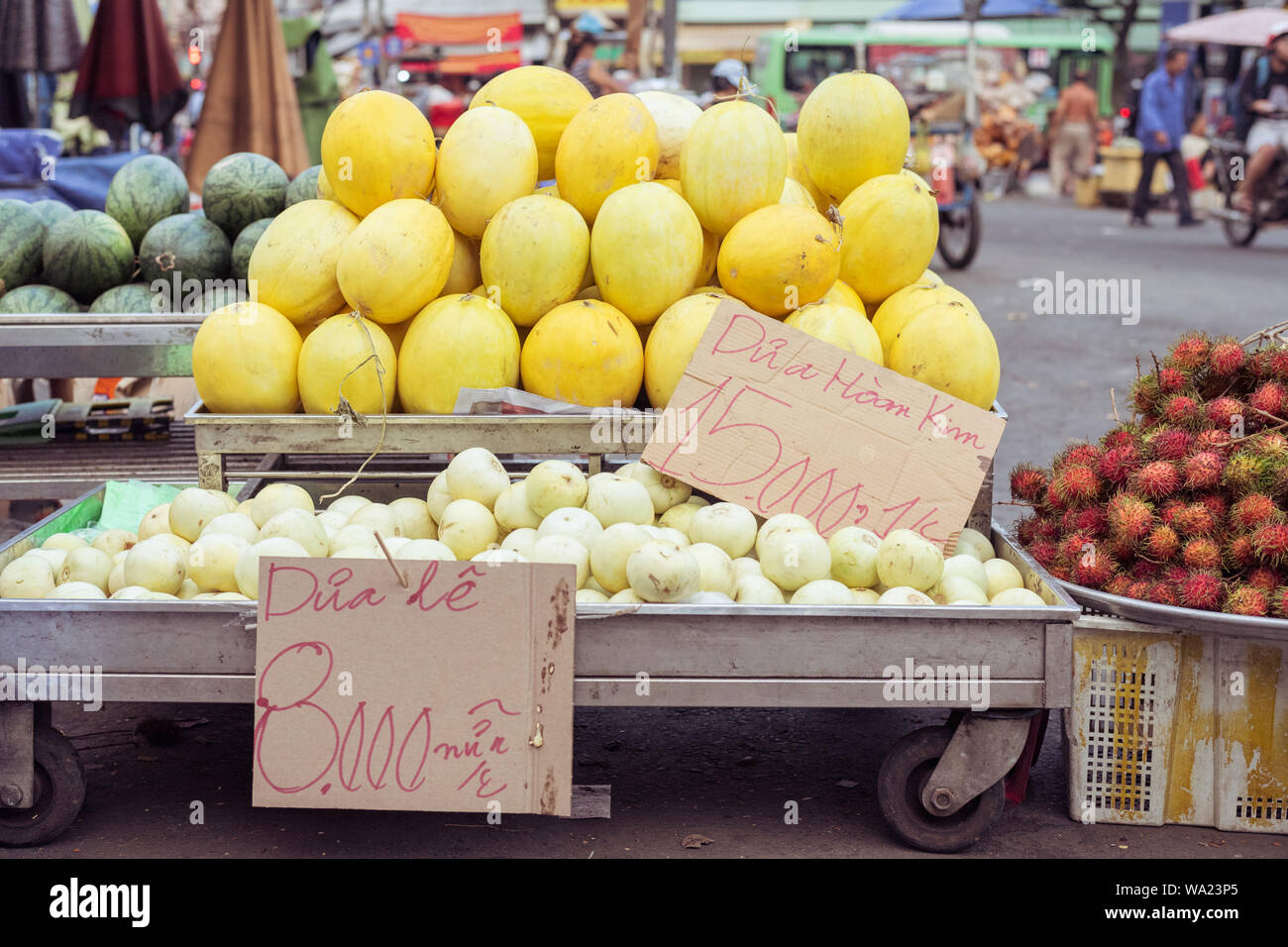 Melonen auf Ständen mit Preis tags: goldene Melone, 15.000 Dong (0,6 $) für 1 kg, Melone und Birne, 8.000 Dong für ein Stück. Markt in Cho Lon, Ho Chi Minh Stockfoto