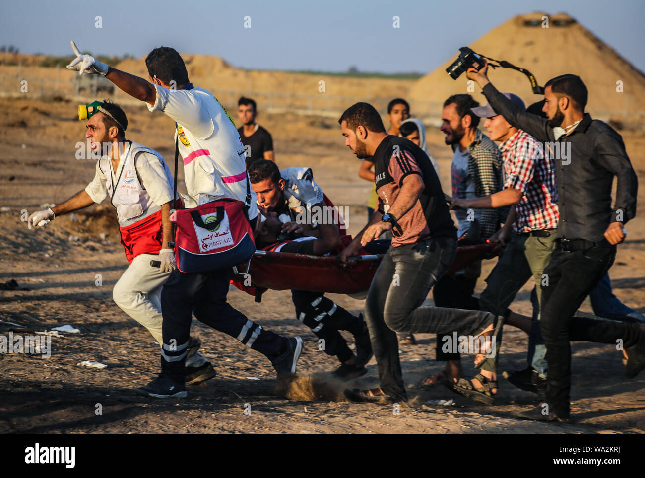 Ärzte tragen eine verletzte Palästinensische bei Auseinandersetzungen zwischen palästinensischen Demonstranten und israelischen Streitkräfte über den Zaun zwischen dem Gazastreifen und Israel in der Nähe von Khan Younis im südlichen Gazastreifen demonstriert fordern die Aufhebung der Belagerung auf der Bürgerschaft seit Jahren auferlegt. Stockfoto