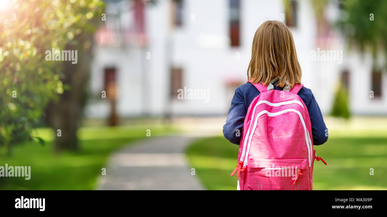 Mädchen mit Rucksack vor einer Schule Stockfoto