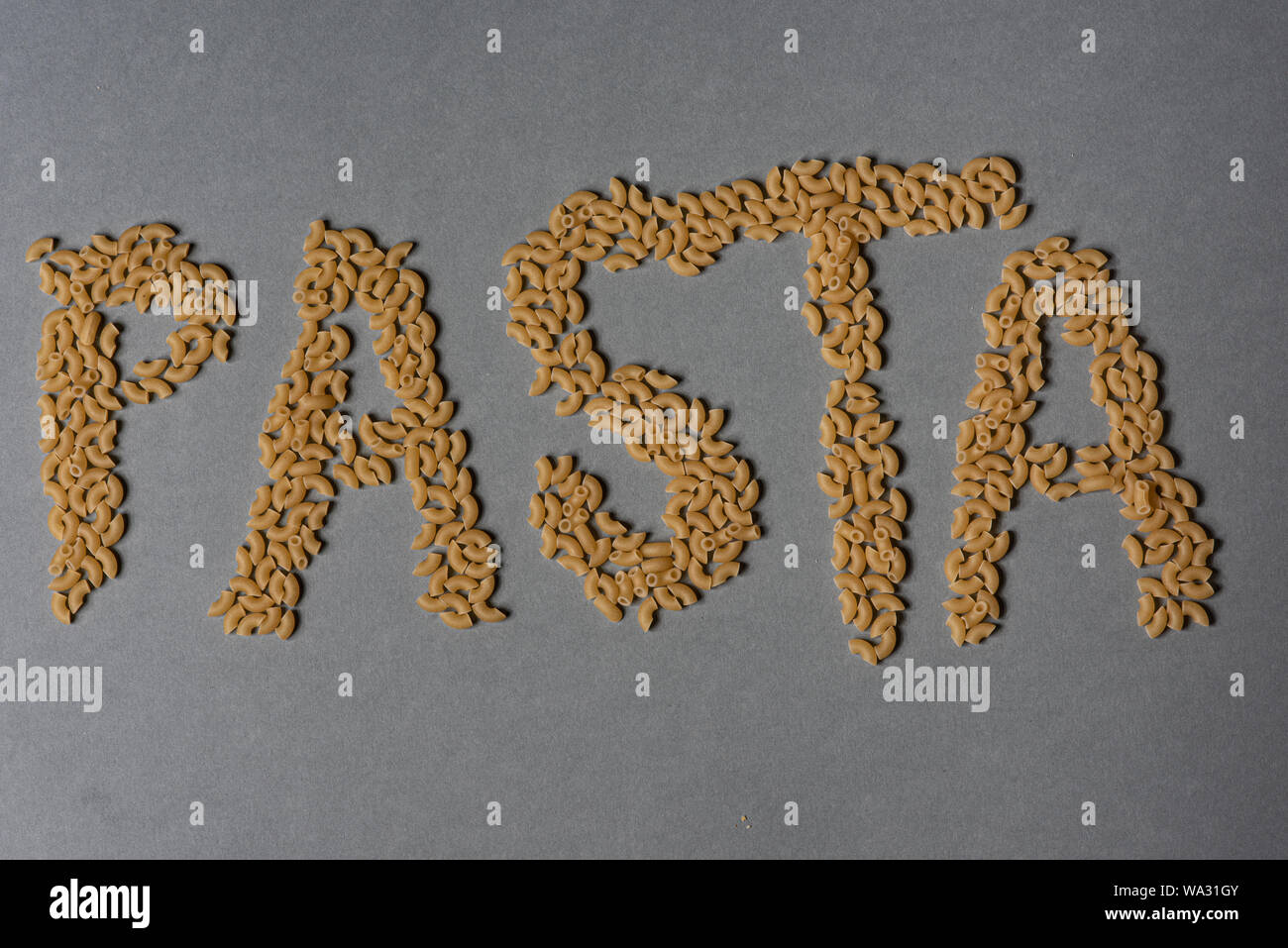 Das Wort "Pasta in Teigwaren auf grauem Hintergrund Stockfoto