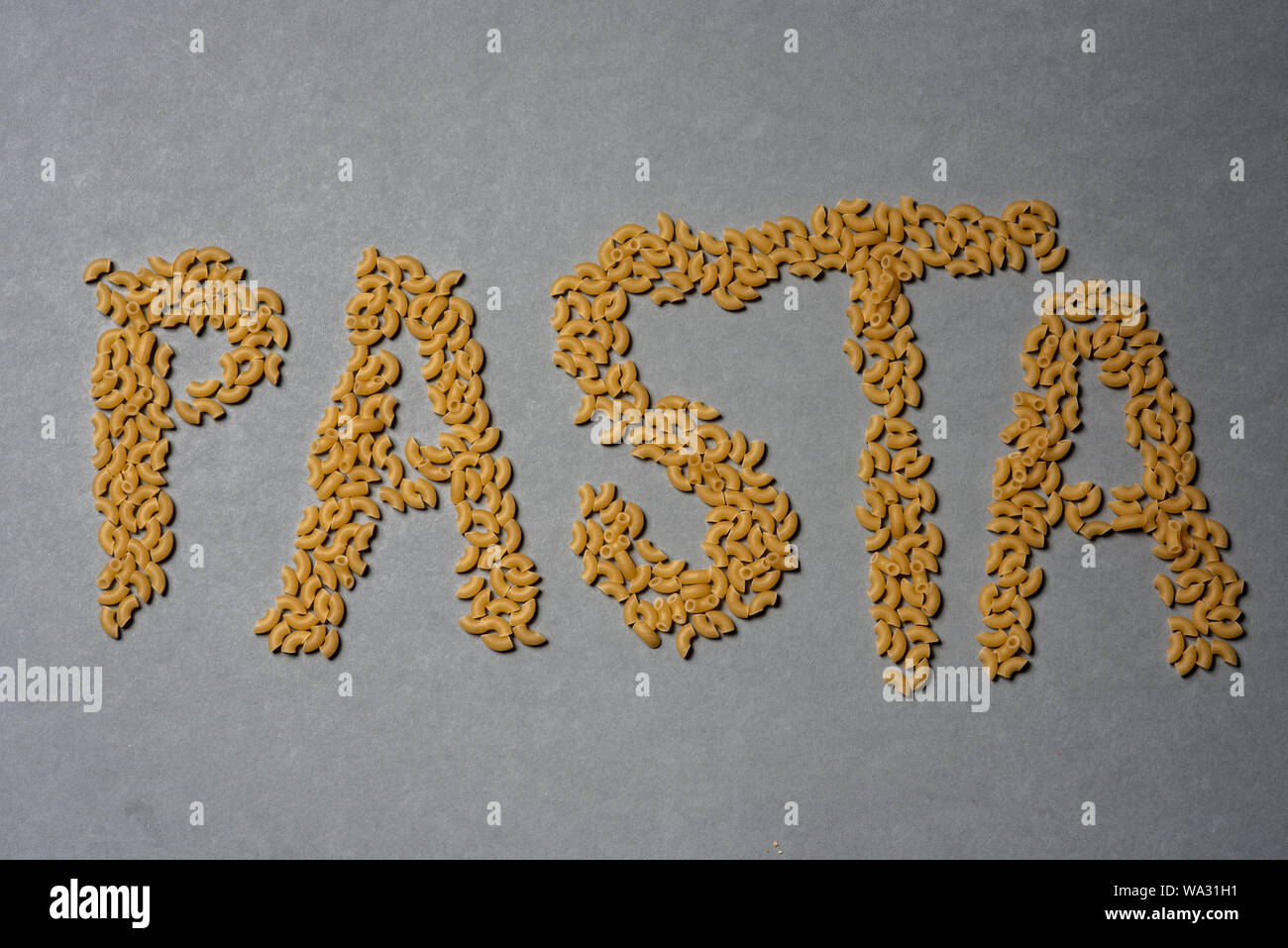 Das Wort "Pasta in Teigwaren auf grauem Hintergrund Stockfoto