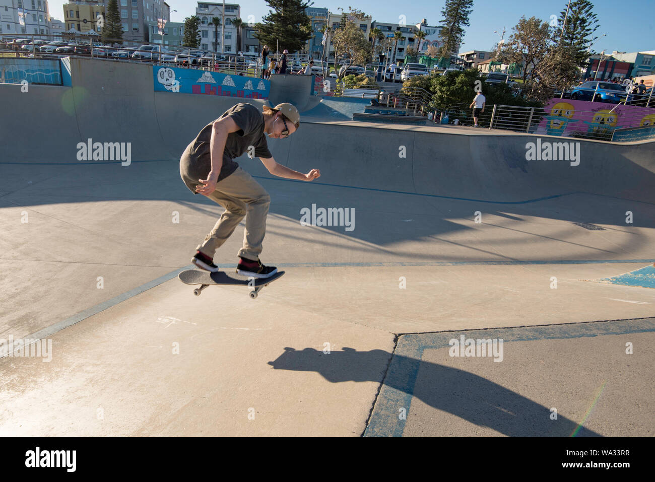 In den späten Nachmittag Sonne am Bondi Beach Skate Park eine junge männliche Skateboarder erhält etwas Luft. Stockfoto