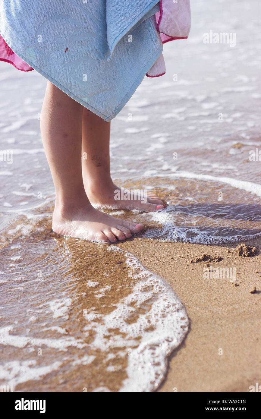 Kleines Mädchen mit Badetuch am Strand bedeckt Stockfoto