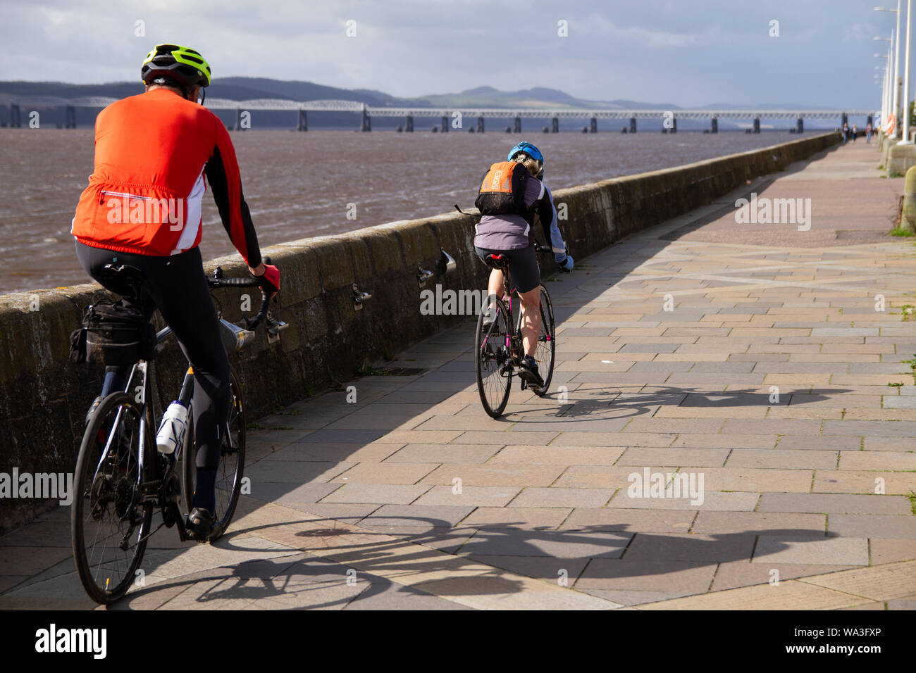 Tayside Dundee, Schottland, Großbritannien, 17. August 2019: BRITISCHE Wetter. Sonnig und kühlen Morgen in Dundee mit verstreuten Duschen später am Tag entwickelt, maximale Temperatur 18°C. Ein paar Radfahrer Radfahren entlang der Stadt Uferpromenade mit Blick auf den berühmten 1800 'Stay Eisenbahnbrücke in der Ferne. Credit: Dundee Photographics/Alamy leben Nachrichten Stockfoto