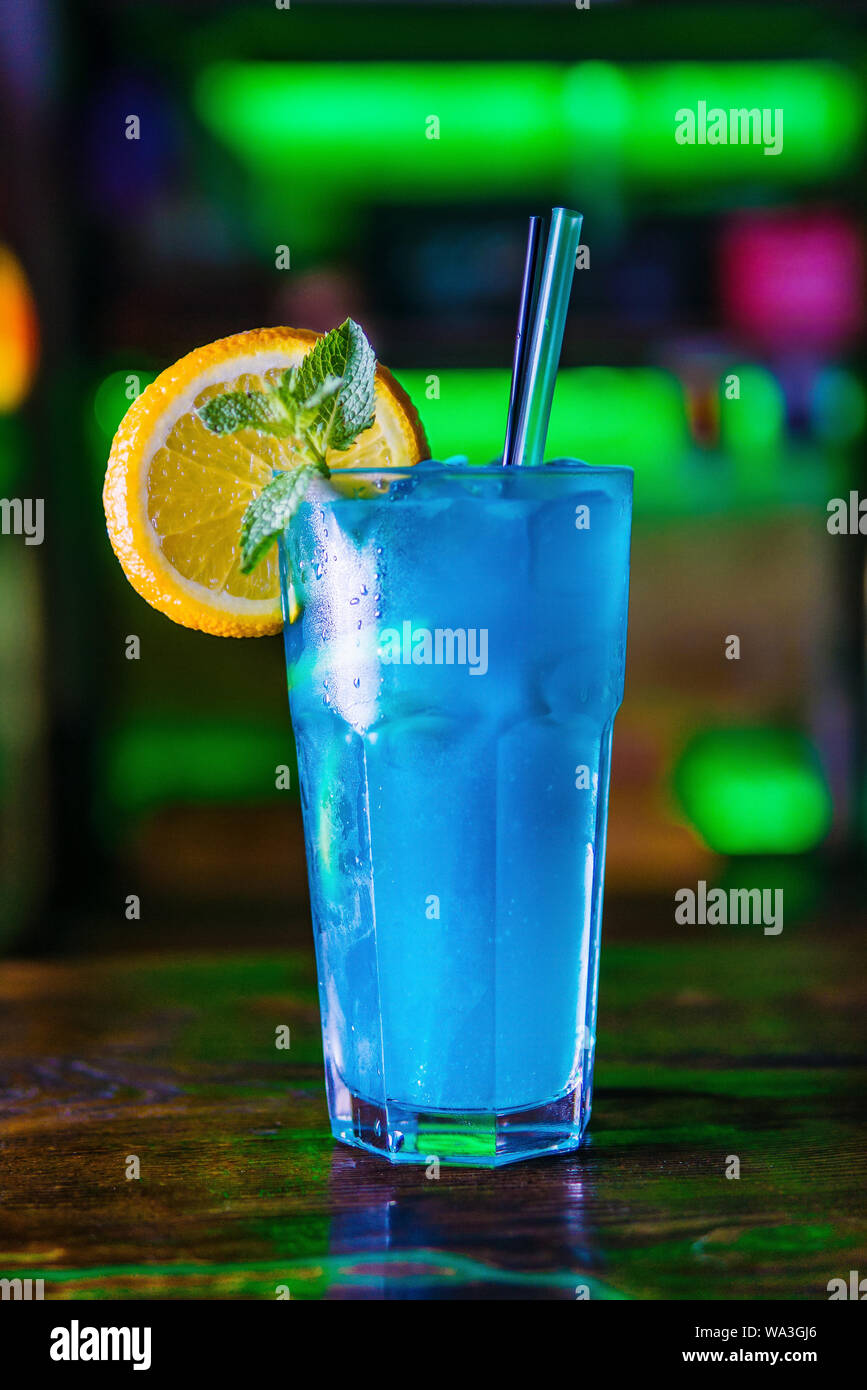 Blue Cocktail in ein hohes Glas Glas mit einer Scheibe Orange. Bunten Cocktail auf der dunklen Rückseite. Cocktail auf einen farbigen Hintergrund in ein hohes Glas. Stockfoto