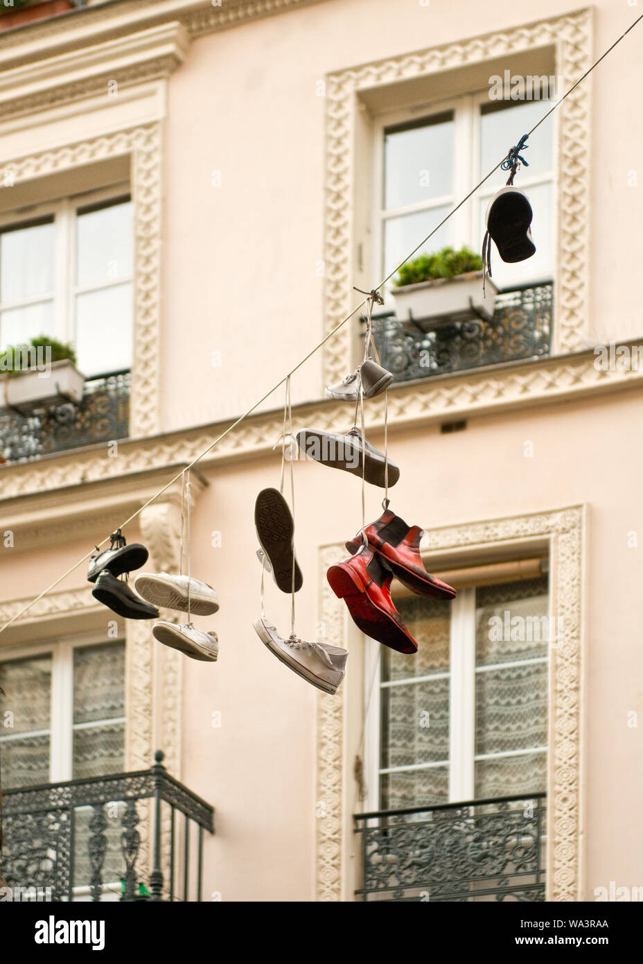 Zeigt hängen durch ihre Schnürsenkel aus Zeile zwischen den Wohnhäusern. Bezirk Marais, Paris, Frankreich Stockfoto