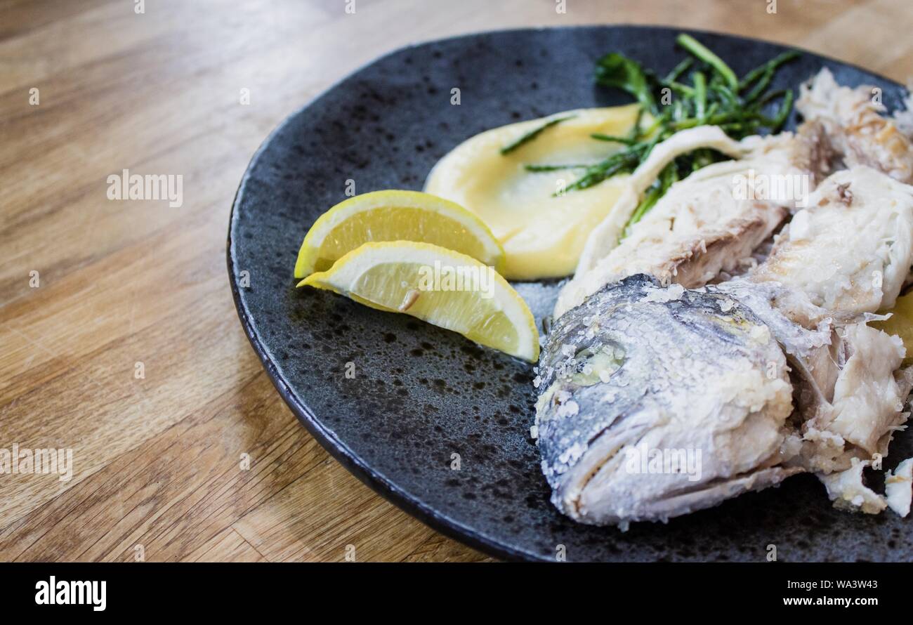 Nahaufnahme eines rohen Fisches mit Zitronen auf einer Runde Platte Stockfoto