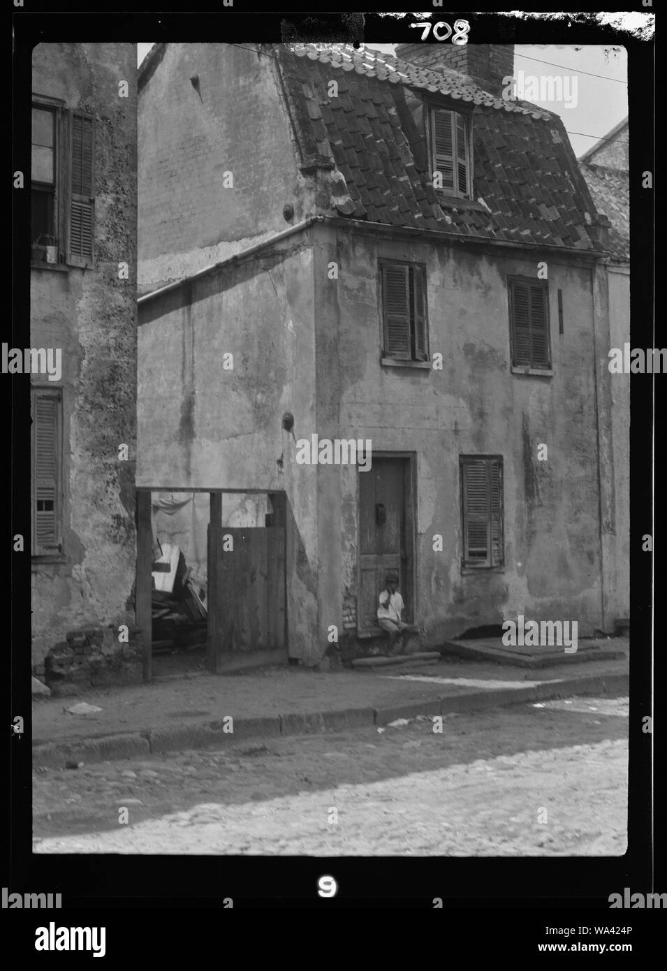 Junge sitzt in der Tür eines zweistöckigen Gebäudes, [17 Chalmers Street], Charleston, South Carolina Stockfoto