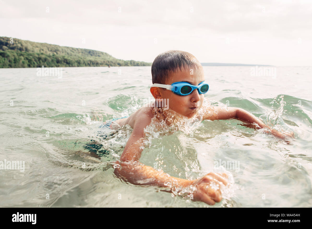 Lustige kaukasischen Jungen Schwimmen im See Fluss mit Unterwasser Schutzbrille niedlich. Kind Tauchen in Wasser am Strand. Authentische echten Lifestyle glückliche Kindheit. Summe Stockfoto