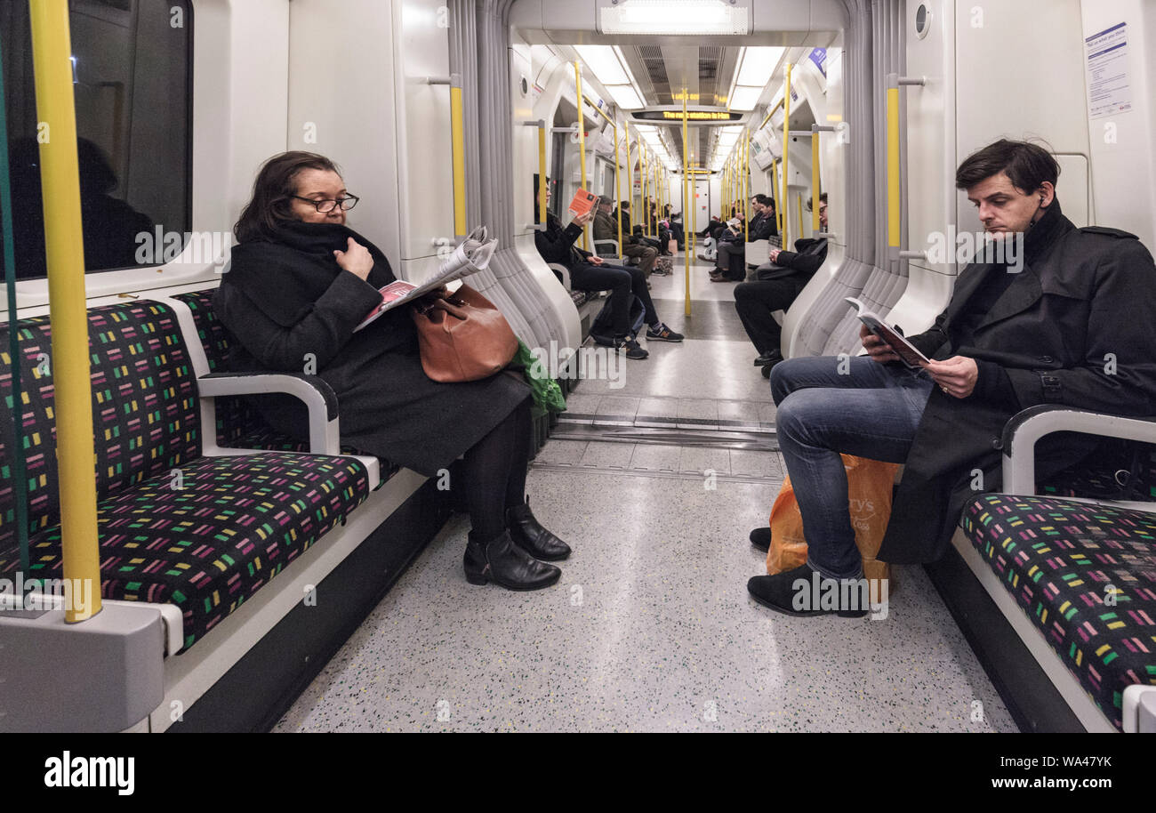 Passagiere lesen und Ignorieren einander sitzen in Stille auf einer Londoner U-Bahn Linie Zug Richtung Westen von der Earls Court Stockfoto
