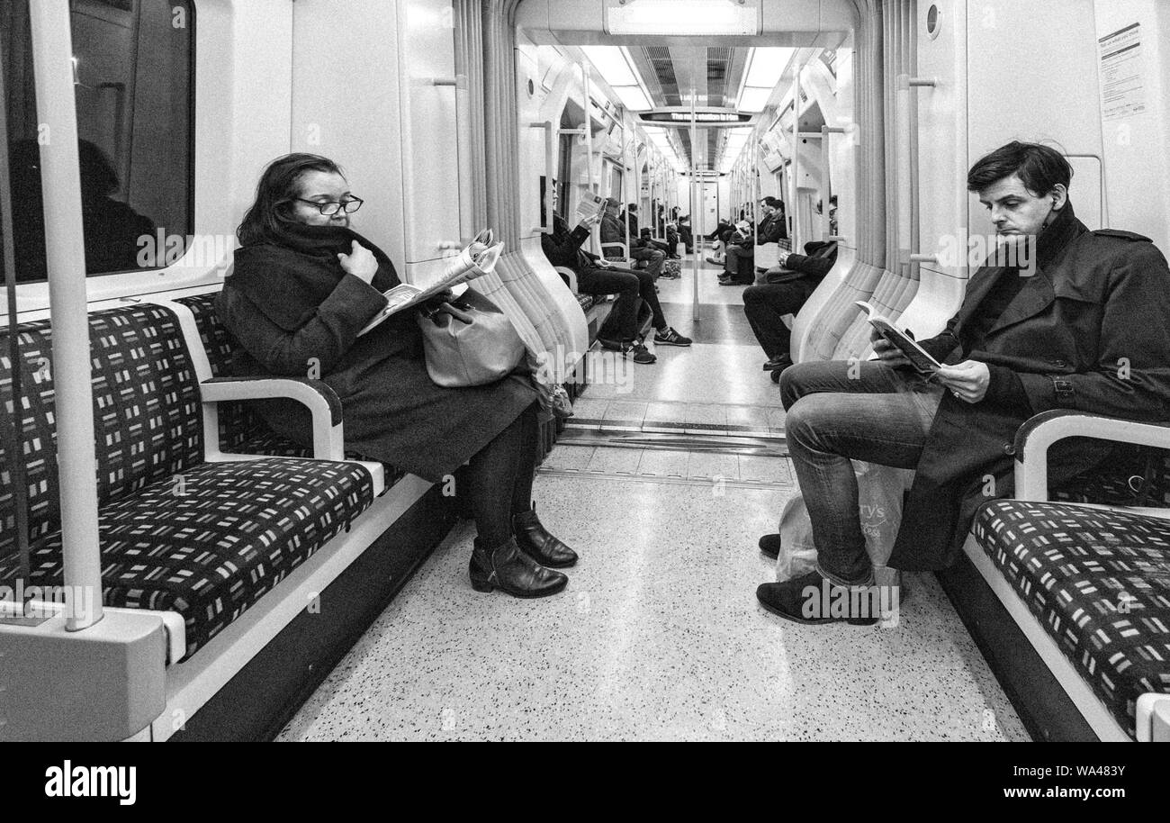 Passagiere lesen und Ignorieren einander sitzen in Stille auf einer Londoner U-Bahn Linie Zug Richtung Westen von der Earls Court Stockfoto