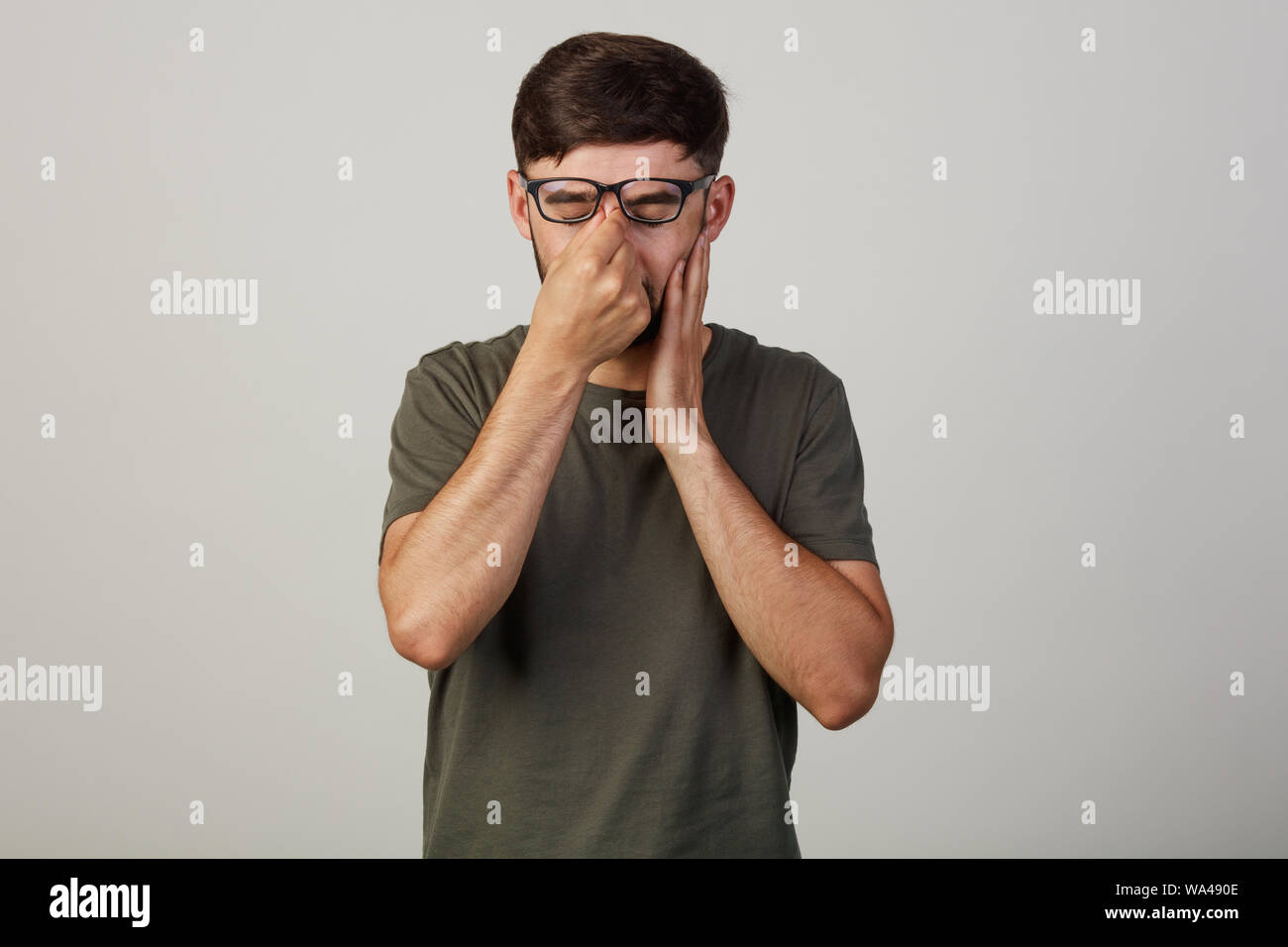 Der junge Mann schloss seine Augen. Schlecht zu sehen. Der Kerl in Brille einen Rest in die Augen bei der Arbeit Stockfoto