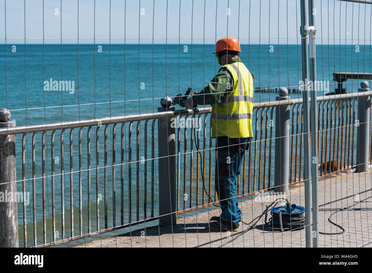 Arbeiter mit Winkelschleifer. Die Arbeit an der Wiederherstellung der Böschung Zaun. 2019-05-30. Kaliningrad, Russland Stockfoto