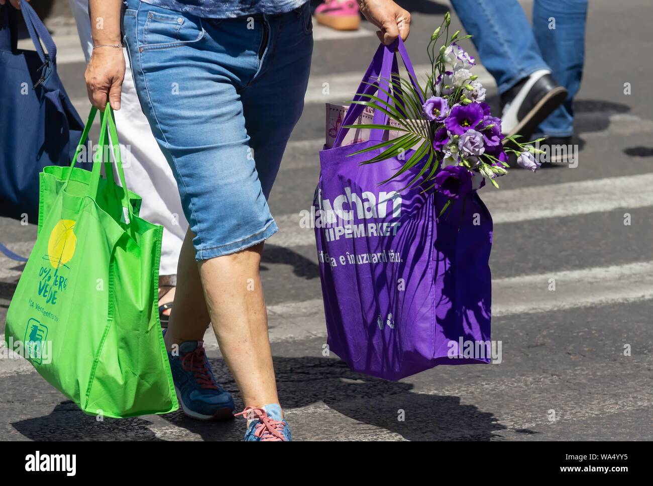 Bukarest, Rumänien - 13. August 2019: Menschen, die einkaufstaschen Überqueren einer Straße in Bukarest. Stockfoto