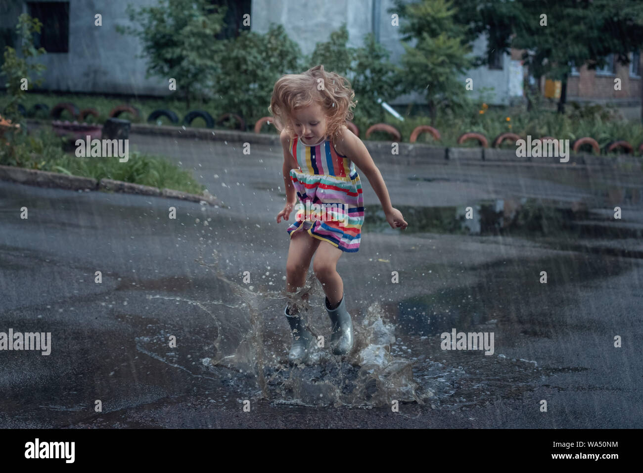 Cute Baby Mädchen in die Pfützen im Regen springen. Stockfoto