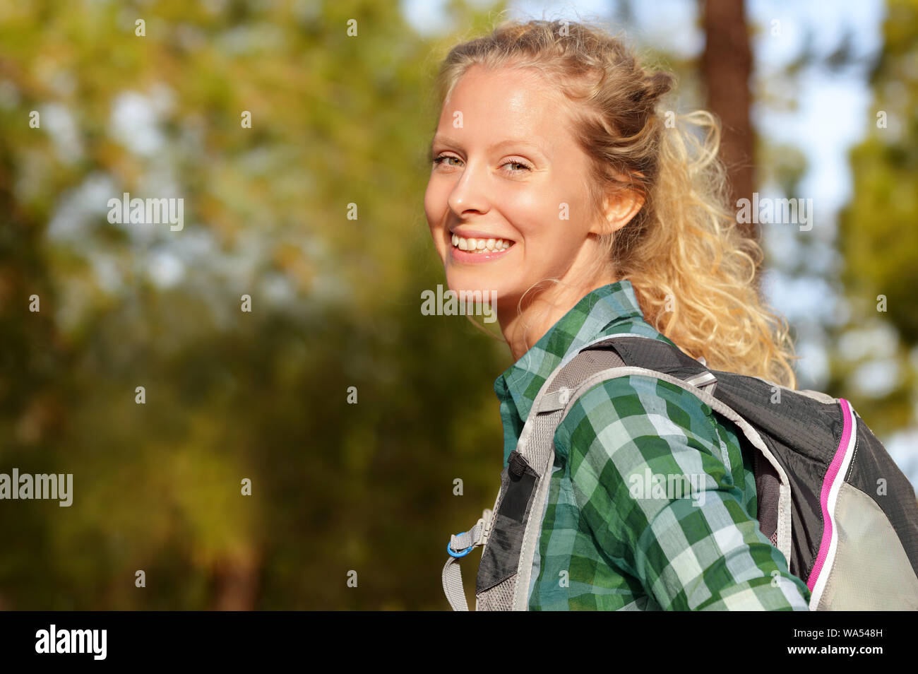 Wandern Frau Porträt Lächeln glücklich im Wald. Weibliche Wanderer Mädchen Trekking Rucksack tragen außerhalb der suche ehrliche und frische an der Kamera. Schöne junge blonde Mädchen, gesunden Lebensstil. Stockfoto