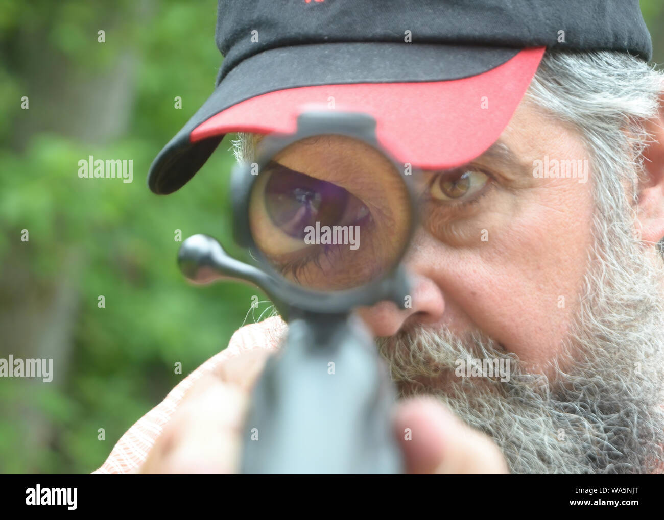 Ein Mann Augen erscheint groß als er Sehenswürdigkeiten in sein Gewehr vor Beginn der Hirsche Gewehrjahreszeit in Waterbury, Vermont. Stockfoto