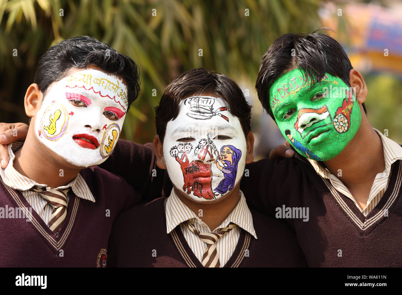 Drei Kinder bemalten sein Gesicht mit Slogan Stockfoto
