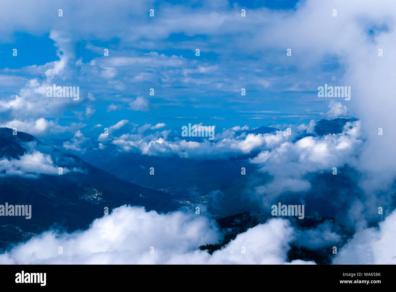 Ansicht von oben, von der Spitze oder einem Flugzeug, in einem bewaldeten Tal mit Siedlungen, teilweise durch cumulus Wolken versteckt Stockfoto