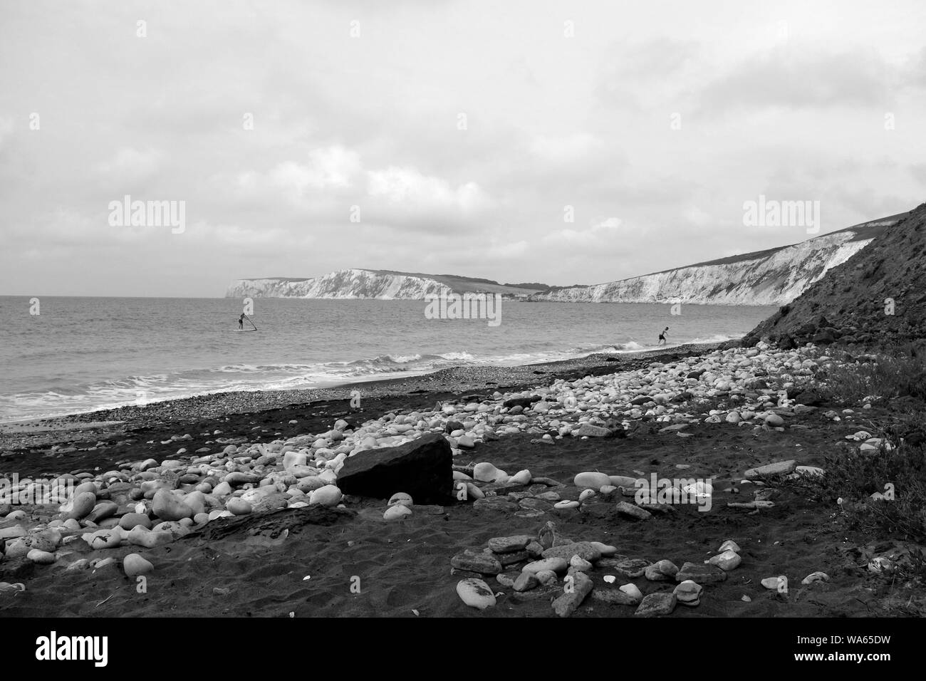 Ein Paddel-boarder und Schwimmer im Meer in Compton Chine Beach Compton Bay auf der Isle of Wight Stockfoto