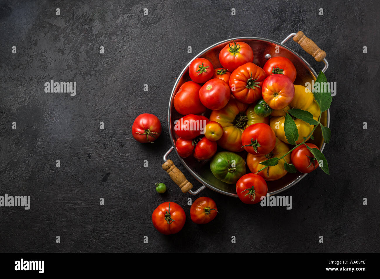 Reife Tomaten in einer Pfanne auf schwarzem Stein, kopieren. Stockfoto