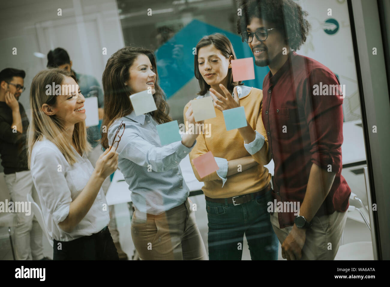 Gruppe junger Geschäftsleute diskutieren Vor der Glaswand mit Post-it Notes und Aufkleber beim Start Büro Stockfoto
