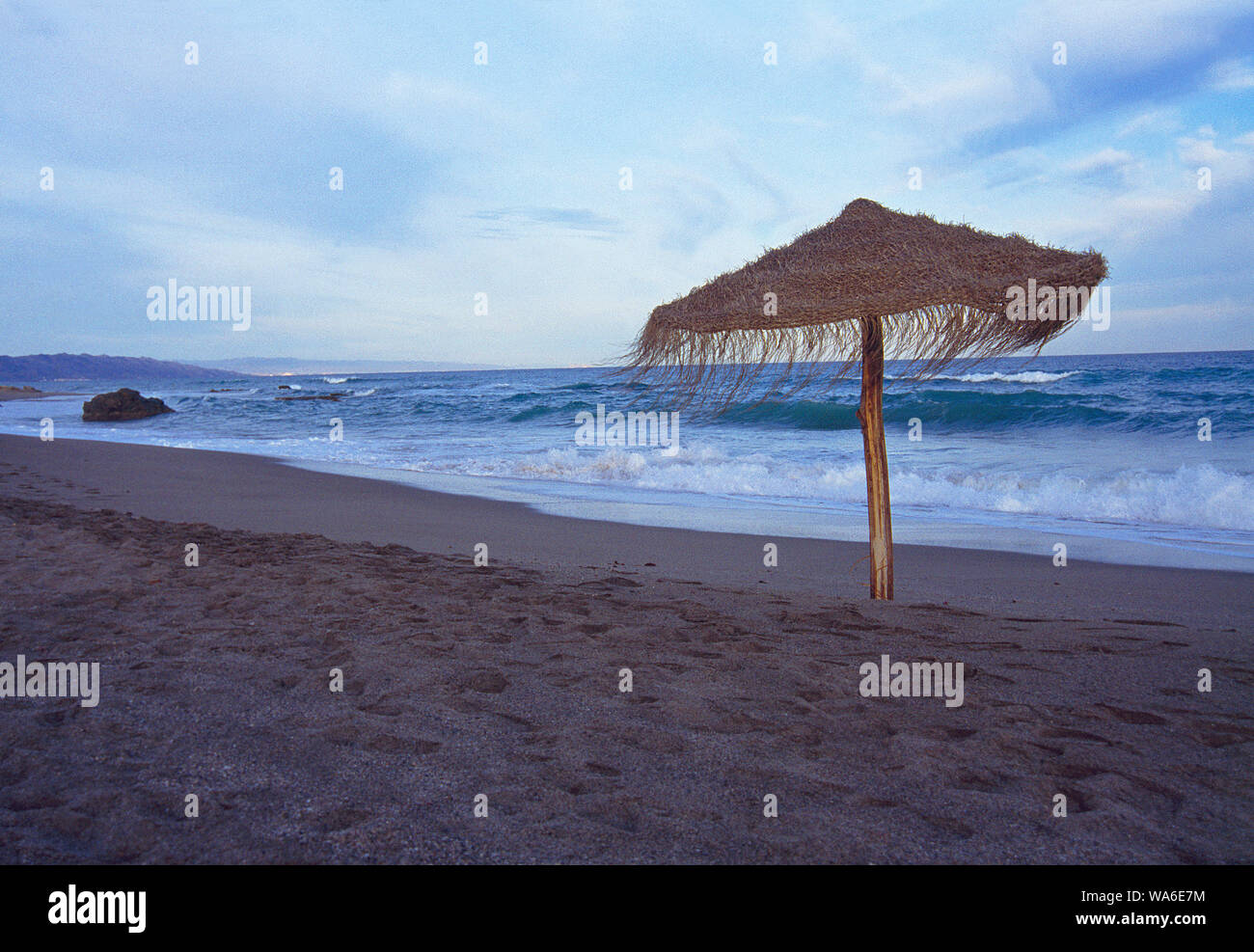 Einsame Sonnenschirme am Strand bei Sonnenuntergang. Mojacar, Almeria Provinz, Andalusien, Spanien. Stockfoto