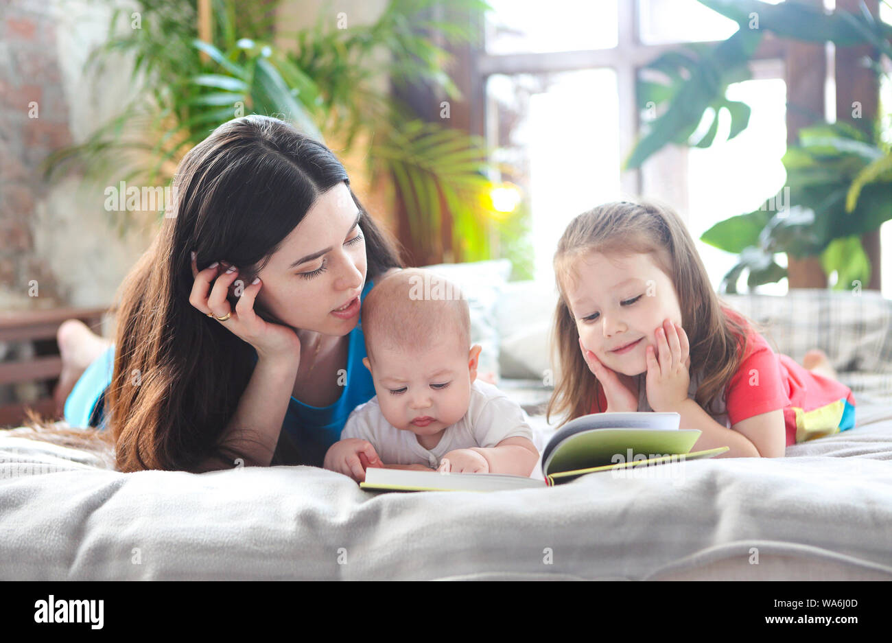 Junge Mutter ein Buch lesen mit ihrer Tochter und ihrem Sohn in Schlafzimmer Stockfoto