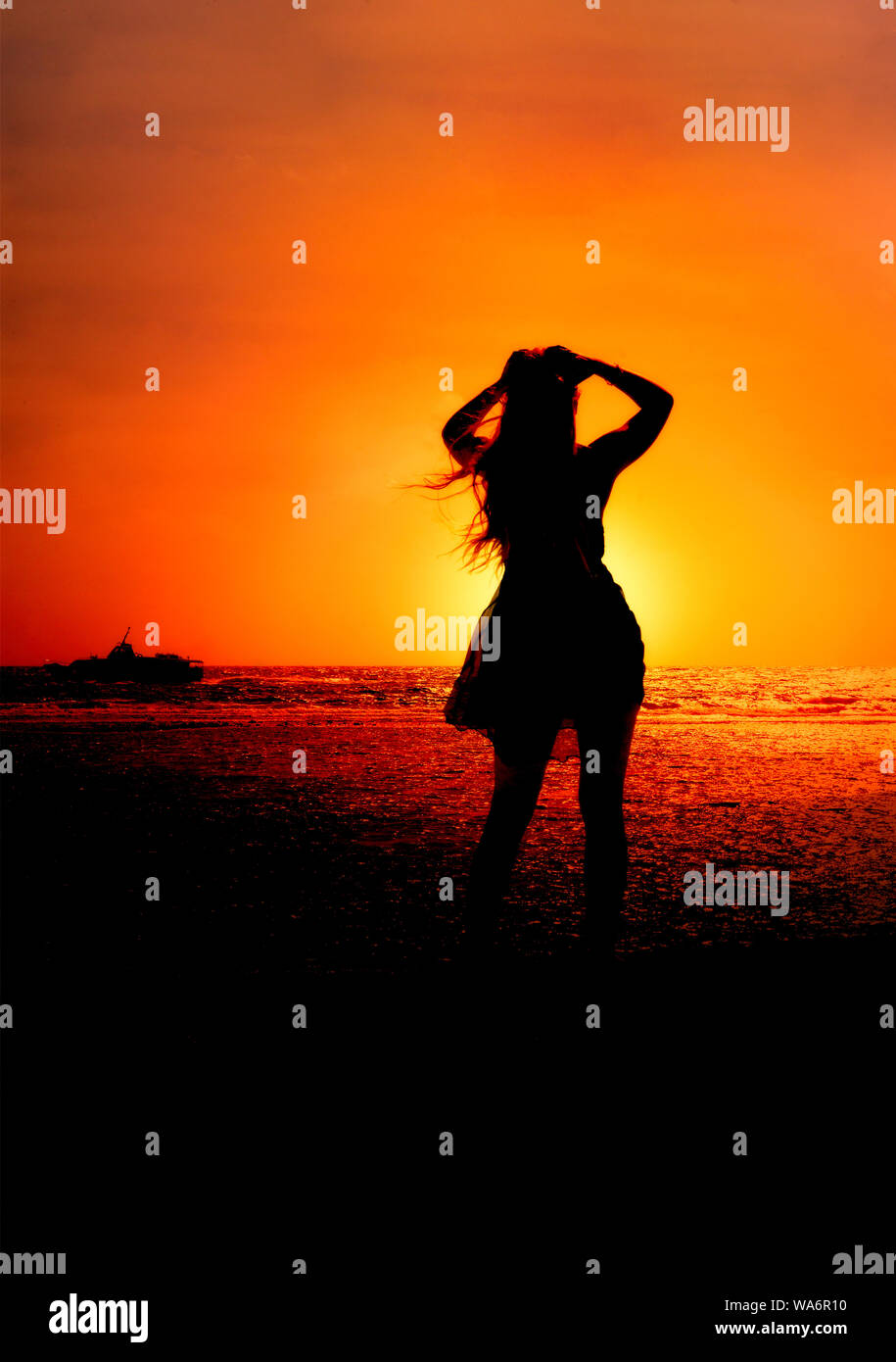 Schöne junge Frau am Meer bei Sonnenuntergang Stockfoto