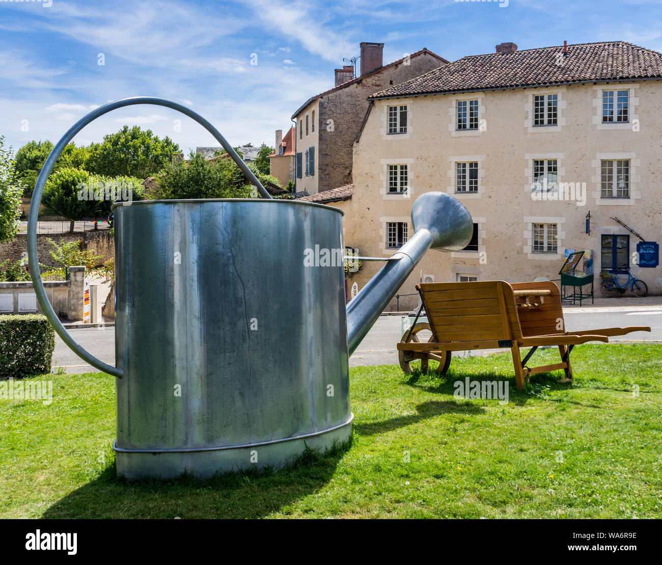 Große Gießkanne und Schubkarre auf Anzeige in 'Buch Stadt Montmorillon, Vienne, Frankreich Stockfotografie
