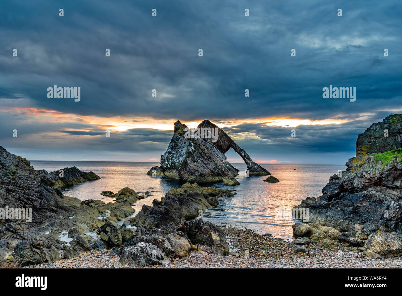 Bogen GEIGE ROCK PORTKNOCKIE Küste von Moray in Schottland am frühen Morgen farbige SONNENAUFGANG MIT EINEM BRUCH IN DEN WOLKEN SOMMER MITTE AUGUST Stockfoto