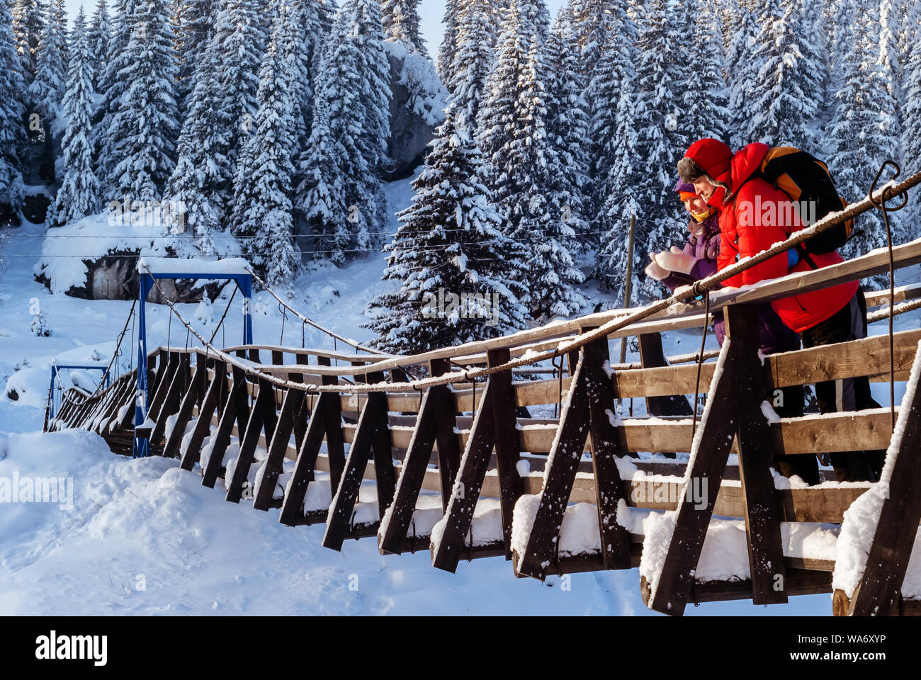Mann und Frau stehen auf eine hölzerne Hängebrücke im Winter vor dem Hintergrund der einen Nadelwald Stockfoto