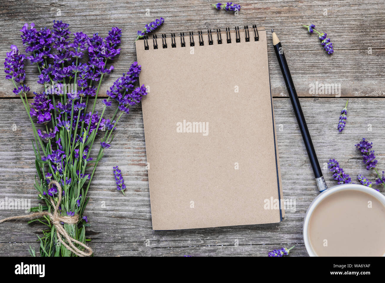Kreatives Layout mit Lavendelblüten, leere Notepad und Kaffee Tasse mit rustikalen Holzmöbeln Hintergrund. Flach. top anzeigen. Hochzeit Hintergrund Stockfoto