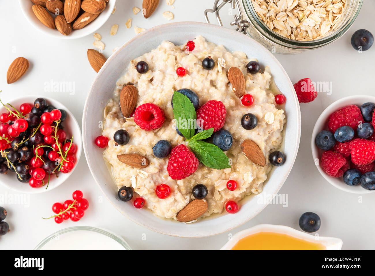 Haferflocken Haferbrei mit frischen Beeren, Nüsse, Honig und Minze in eine Schüssel für gesunde Ernährung Frühstück. top View Stockfoto