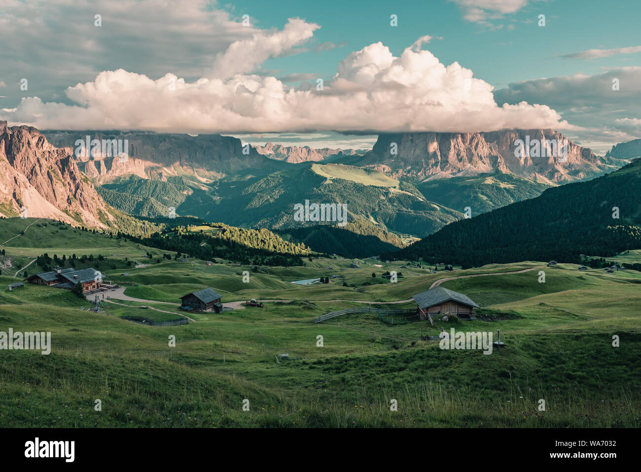 Wunderschöne Aussicht auf der Seiser Alm oder Seiser Alm mit langkofel oder Langkofel Berg in Wolken von Seceda bei Sonnenuntergang. Bergwiese mit Holz- c Stockfoto