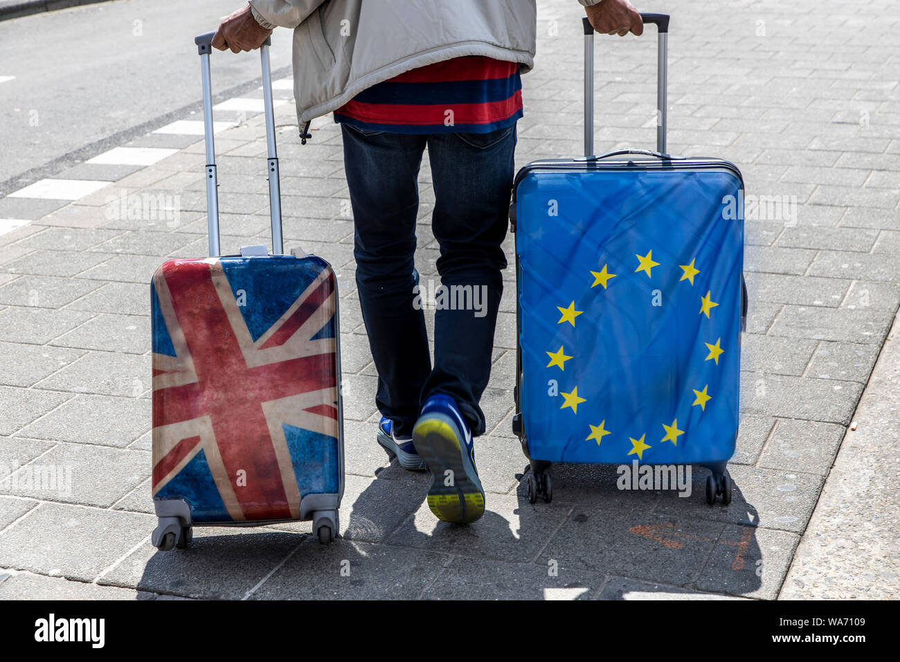 Symbol Bild Brexit, Mann mit 2 Rollen Koffer, einmal mit Union Jack, und Europa Flagge Design, Stockfoto