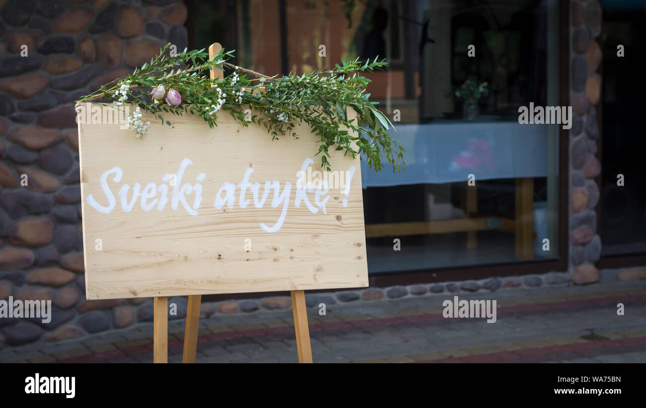 Schild am Eingang von einer Hochzeit Feier Abendessen in weißen Buchstaben auf einem Holzbrett geschrieben und mit Pflanzen dekoriert Willkommen Stockfoto