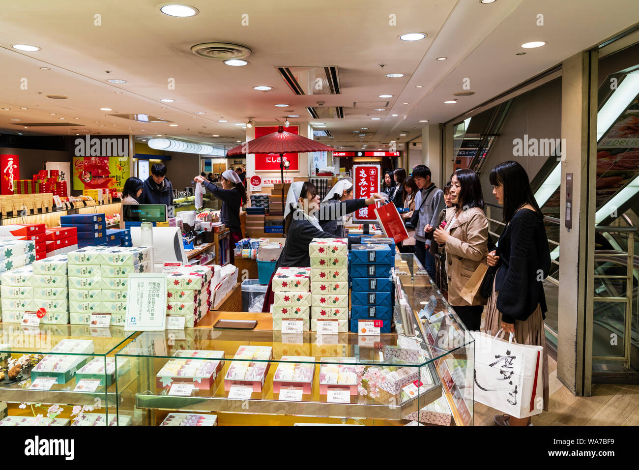 Japan, Hiroshima Station. Shopping Bereich. Süße bean Shop mit Glas und mit Frau Übergabe Tasche Frauen Kunden. Stockfoto