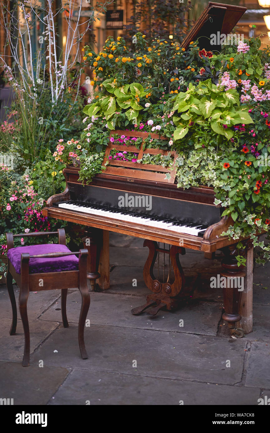 Ein Vintage Piano mit schwarzen und weißen Tasten mit Efeu und anderen Blumen dekoriert. Hochformat. Stockfoto