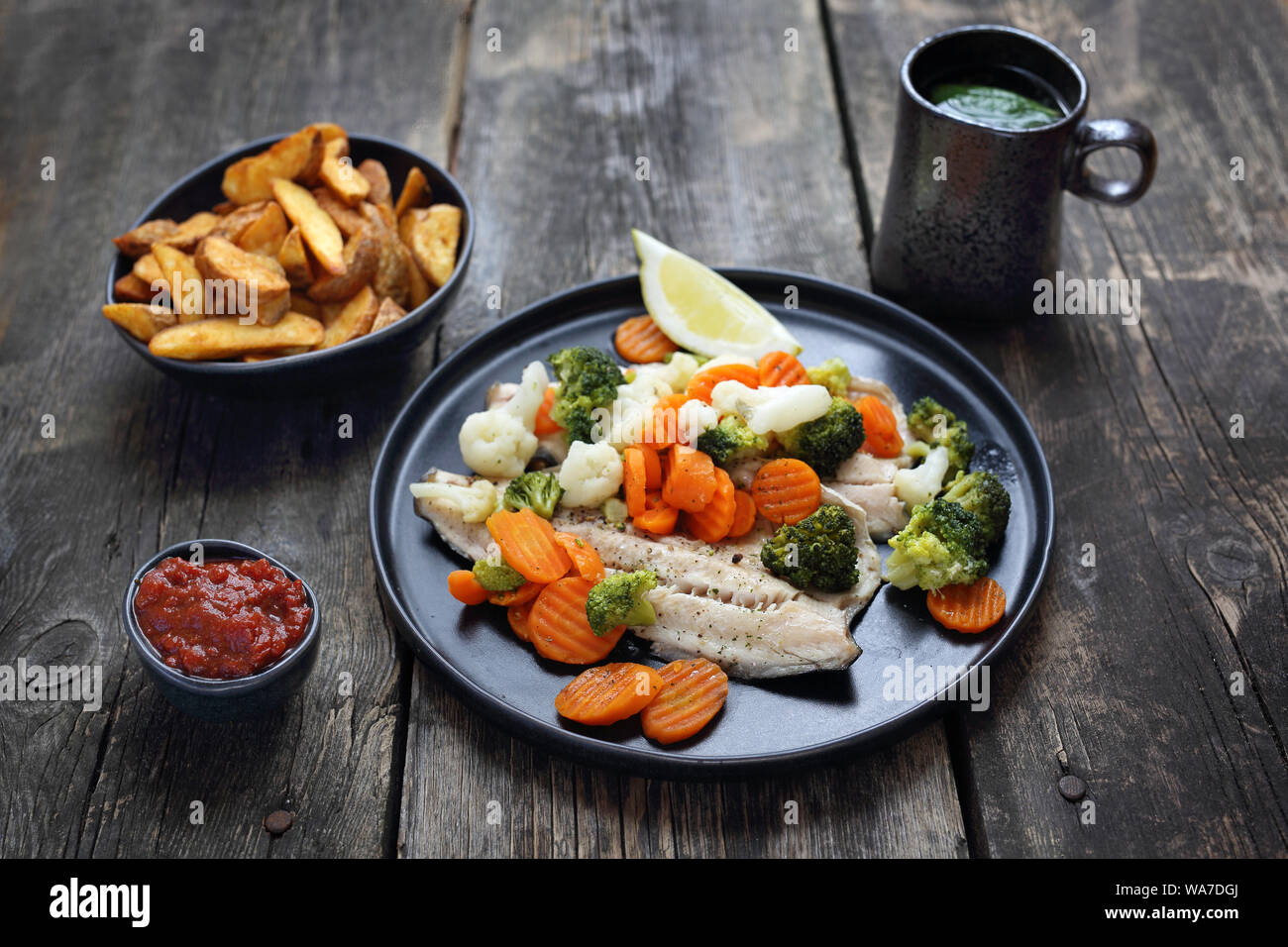 Gegrillter Fisch mit Gemüse, Pommes und Ketchup. Abendessen serviert. Gesunde Ernährung Stockfoto