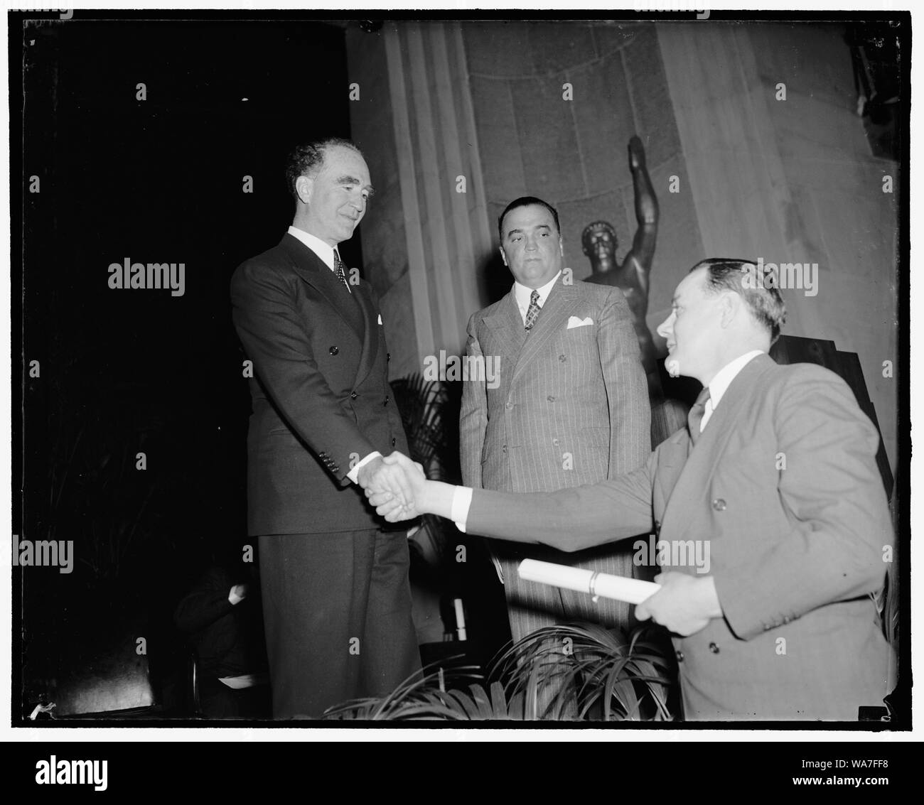Attorney General Auszeichnungen Diplome an Absolventen des F.B.I. Police Academy. Washington, D.C., den 1. April. Kennzeichnung Abschluss einer 12-wöchigen Kurs in der Strafverfolgung, Attorney General Frank Murphy heute verliehen Diplome an 37 Absolventinnen und Absolventen des Fbi National Police Academy. John-F.-Holz der Norfolk, Va., Polizei und Präsident der Abschlussklasse, wird dargestellt, sein Diplom von Attorney General Murphy während F.B.I. Chief J.Edgar Hoover an schaut. 4-1 - 39 Stockfoto