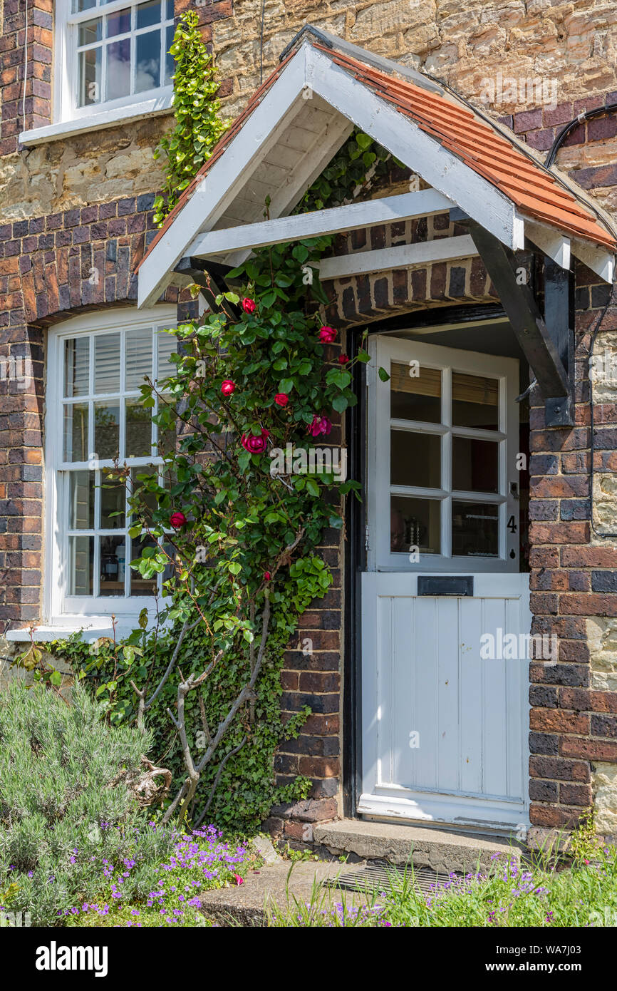 STOKE BRUERNE, NORTHAMPTONSHIRE, Großbritannien - 10. MAI 2019: Hübsche halbe Tür auf georgianischen oder frühviktorianischen Canalside Cottage mit Rosen, die daneben wachsen Stockfoto