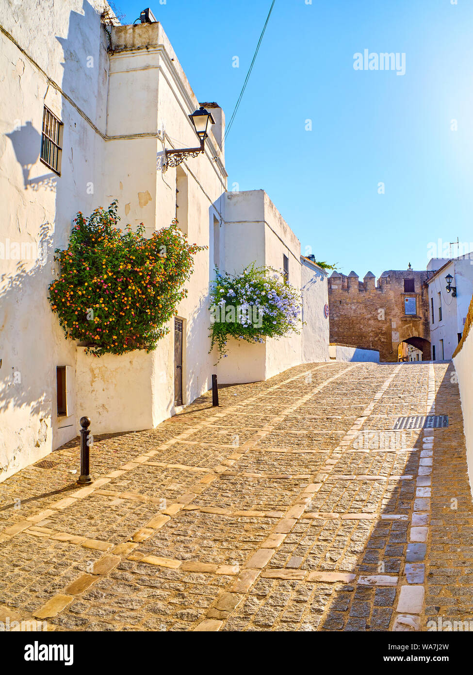 Marques de Tamaron Straße, eine typische Straße der weiß getünchten Wänden von Vejer de la Frontera Innenstadt mit La Segur Tor im Hintergrund. Vejer de la Fr Stockfoto