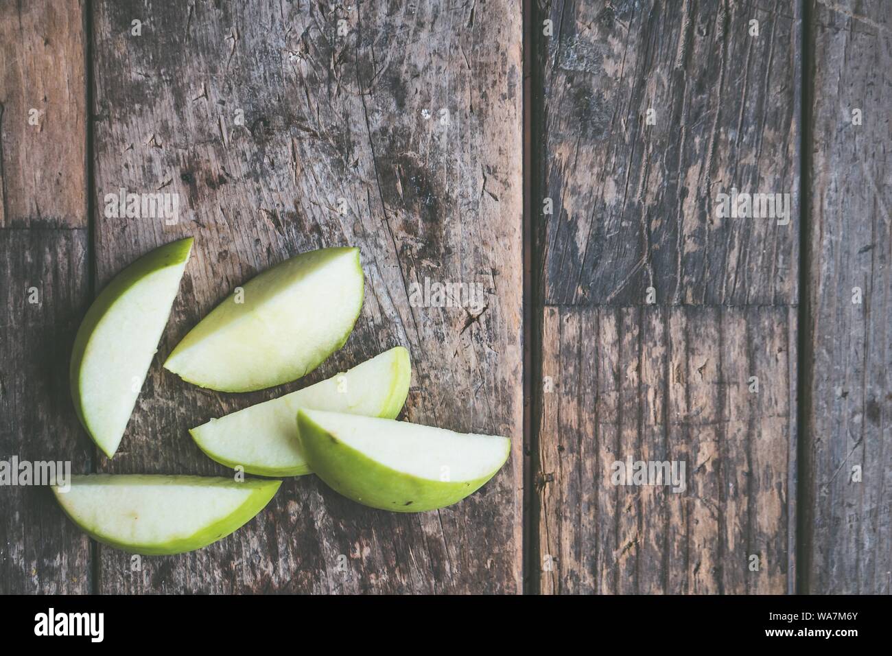 Nahaufnahme über Schuss eines in Scheiben geschnittenen grünen Apfels auf einem Holzhintergrund Stockfoto