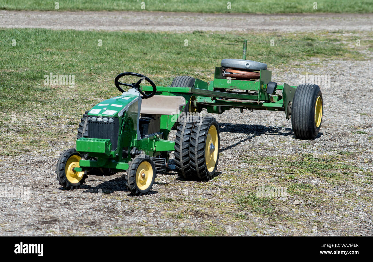 Eine kleine grüne Trettraktor für Kinder, ist mit schweren Gewichten in einem altmodischen Traktor ziehen gewichteten Stockfoto
