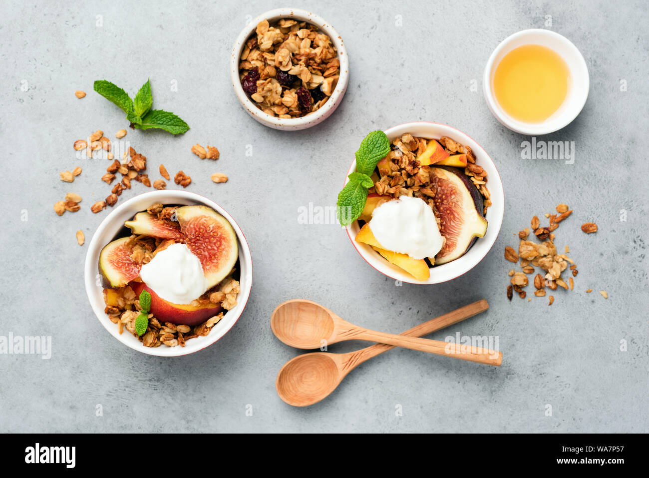 Feigen mit Joghurt und Honig und Haferflocken Müsli auf grauem Beton Hintergrund. Tabelle Ansicht von oben. Gesunde Ernährung Stockfoto