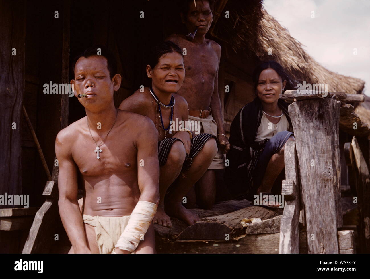 AJAXNETPHOTO. 1955 (ca.). INDO CHINA. VIETNAM. (IN-COUNTRY ORT UNBEKANNT.) - FAMILIE GRUPPE POSIEREN FÜR DIE KAMERA AUF DER VERANDA IHRER strohgedeckten Haus (HOOCH). Foto: JEAN CORRE/AJAXREF: 2 JC 1955 Stockfoto