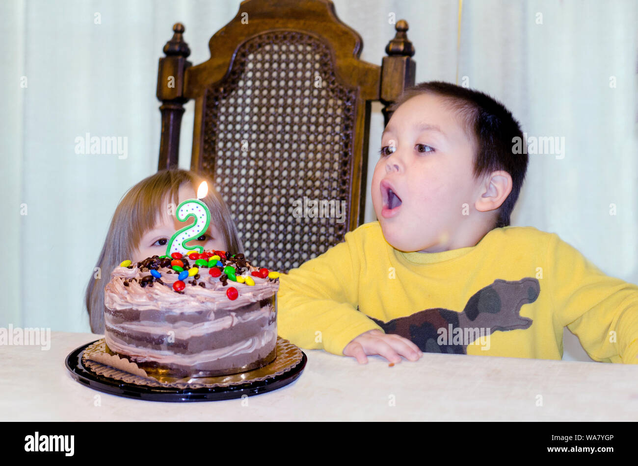 Little boy Ausblasen Kerzen auf seiner Schwester Geburtstagstorte Stockfoto