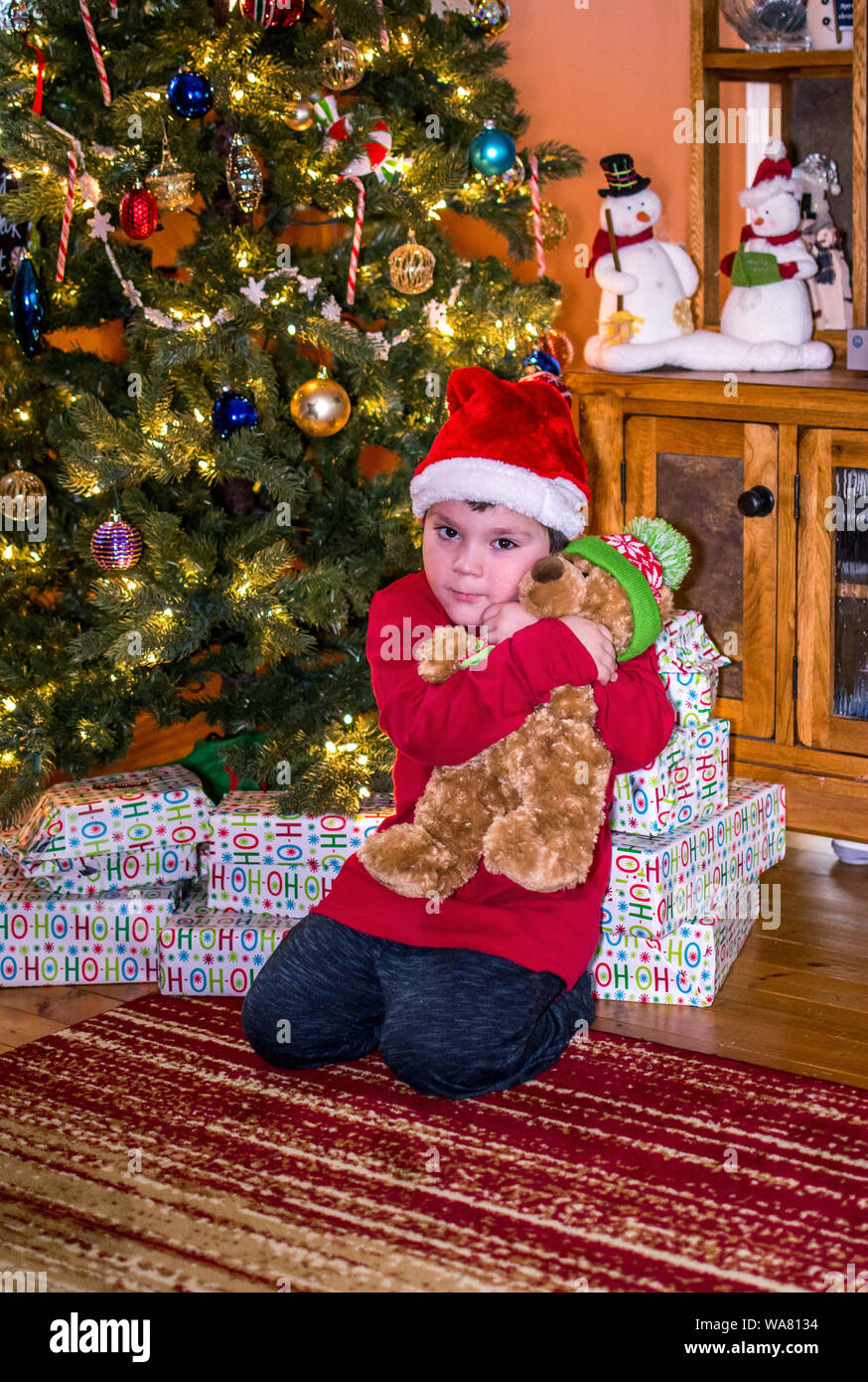 Little boy Umarmungen Neue teddybär unter dem Weihnachtsbaum Stockfoto