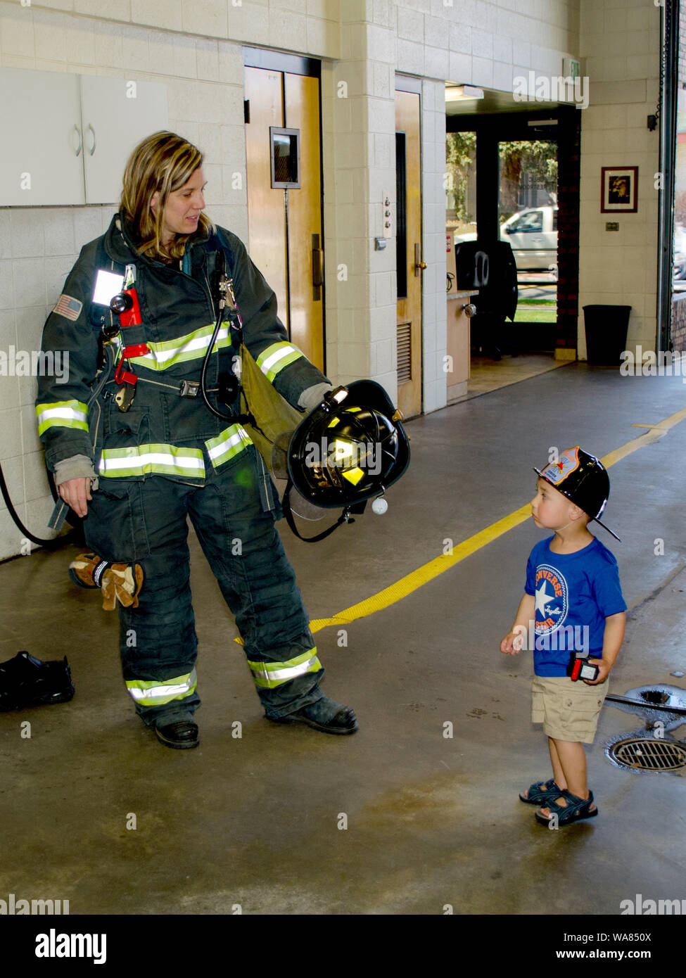 Thornton Colorado USA 14 Juli 2014; eine weibliche Feuerwehrmann zeigt ein Junge wie ein furchtsames Uniform immer noch jemanden sicher versuchen, sie in einen Brand zu helfen Stockfoto